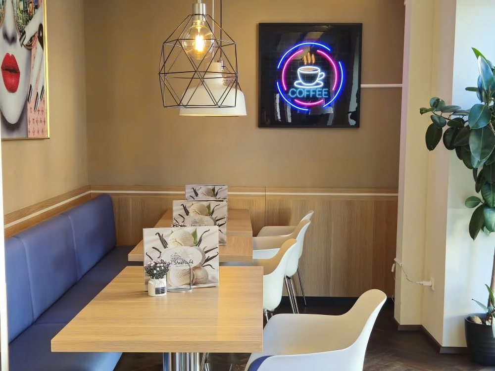 Sitzecke mit blauer Bank, Holztisch und Kaffee-Leuchtschild