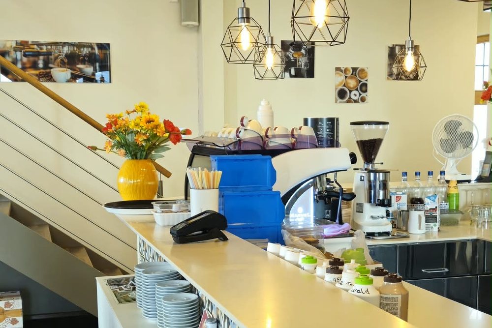 Theke des Stadtcafés mit Kaffeemaschine, Tassen und Blumen